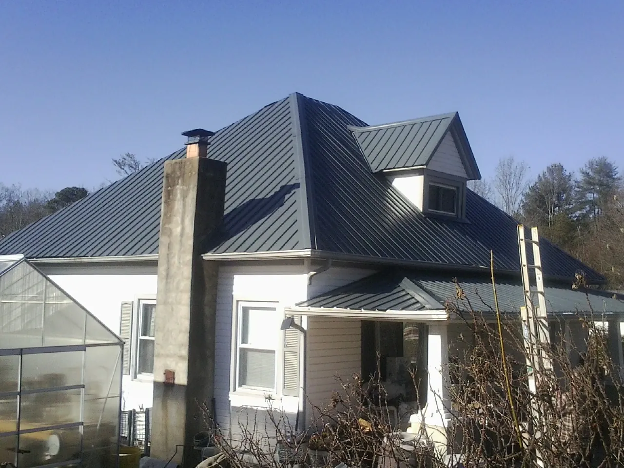 Dark blue standing seam metal roof on a white farmhouse with dormer — Slate & Tile Roof Repair by Roofing Brothers in Christmas
