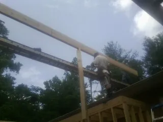 Carpenter setting a ridge beam over a new addition frame — Ice Dam Removal by Roofing Brothers in Christmas