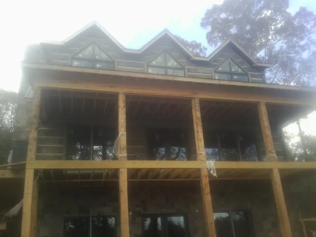 Dormers and porch framing on a large log home under construction — Roof Coating work by our crew in Christmas
