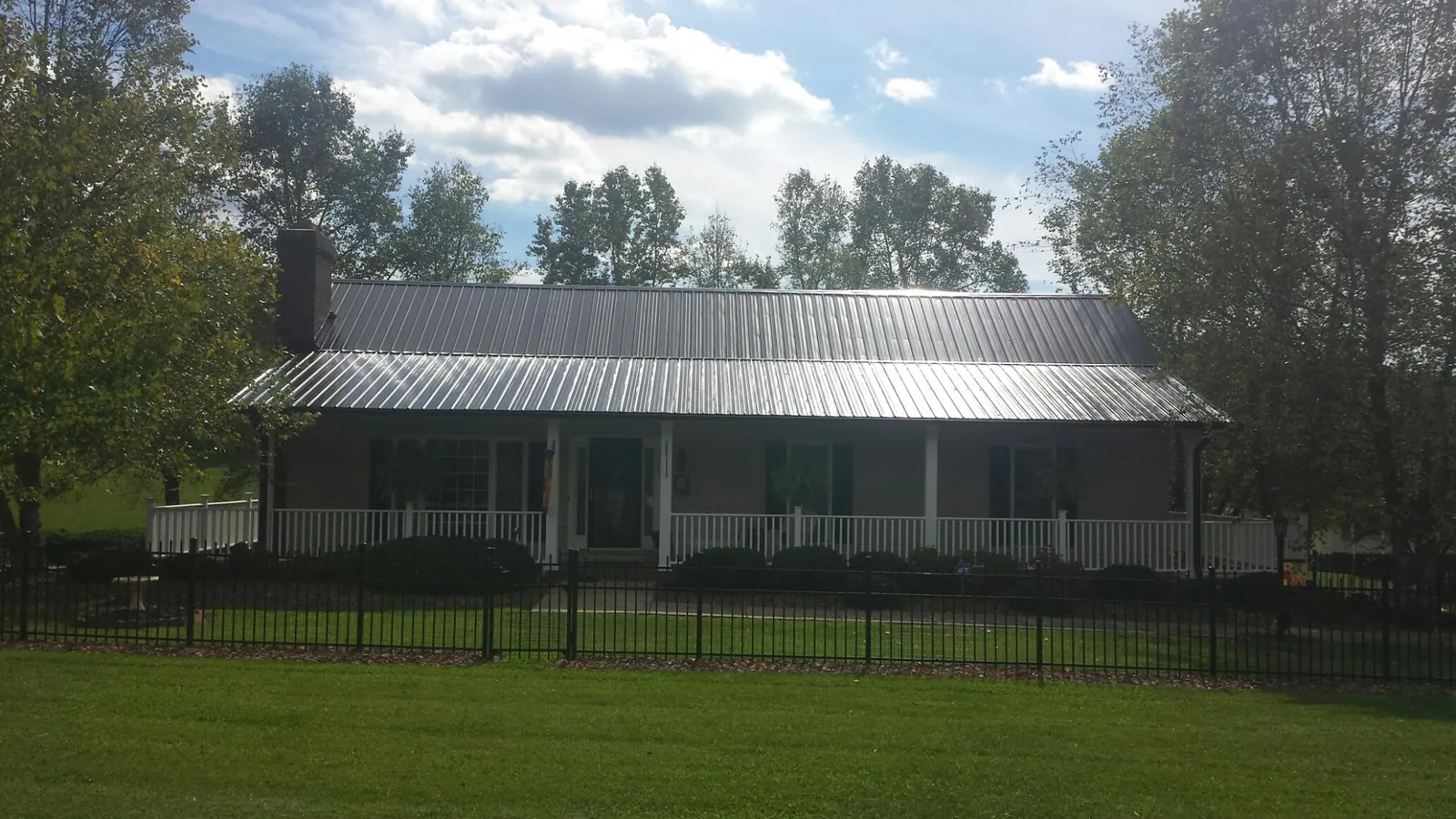 Gray metal roof on a brick ranch with a full width front porch — Gutter Guard Installation work by our crew in Christmas