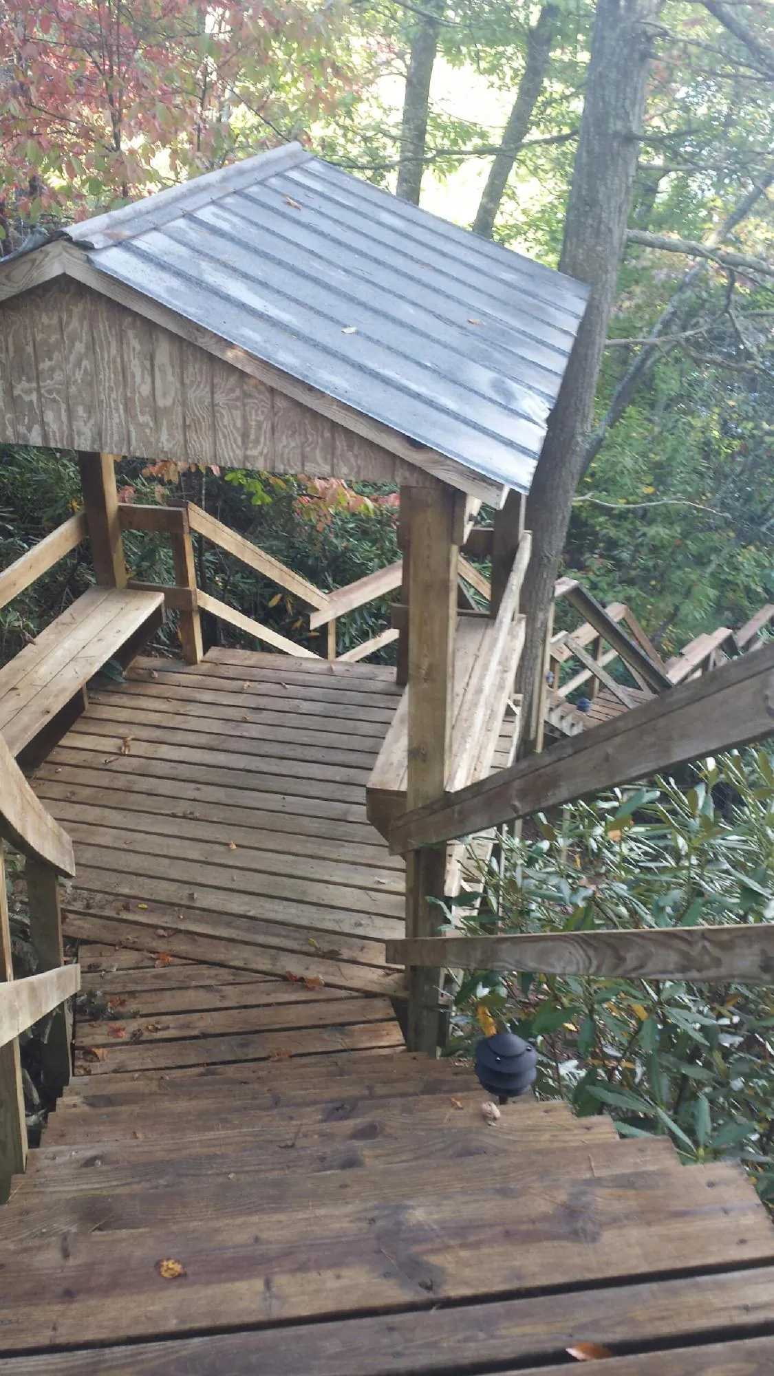 Metal roofed shelter over wooden steps on a wooded walkway — Skylight Repair & Installation work by our crew in Christmas