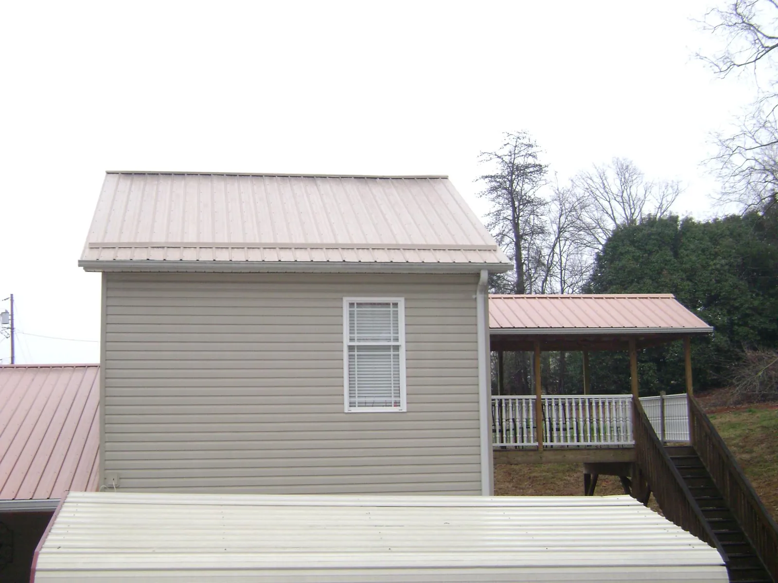 Tan metal roofs on a two story addition and attached porch, from a Roof Replacement job in Christmas