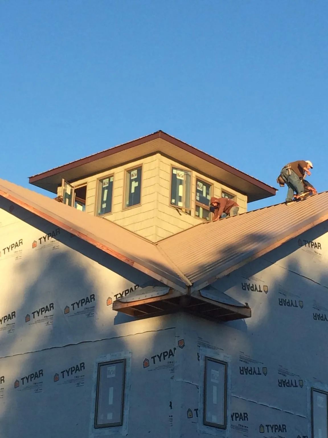 Roofers working around a rooftop cupola on a new metal roof at sunset — Roof Waterproofing in Christmas by Roofing Brothers